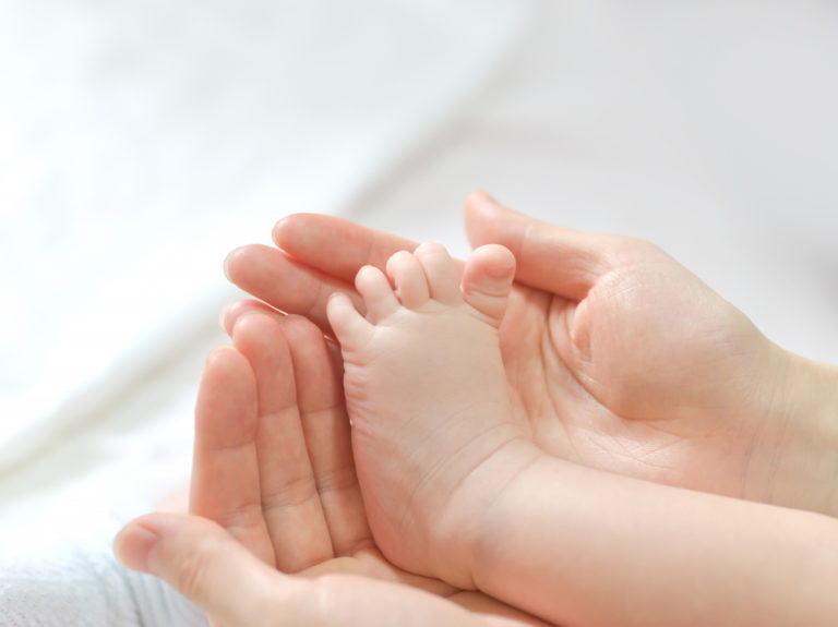 baby feet in mother hands 768x575